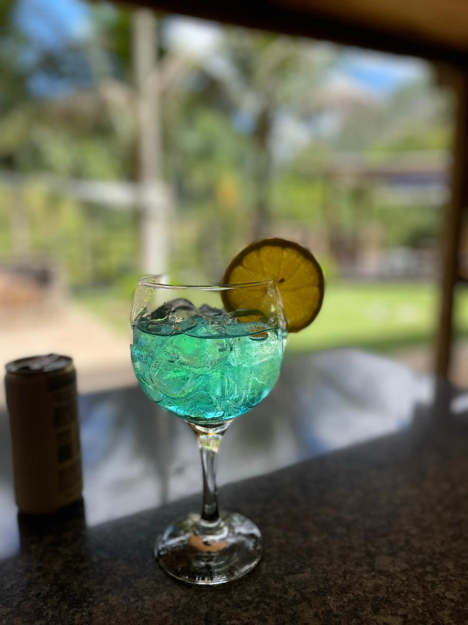 Drinque azul com limão servido no deck