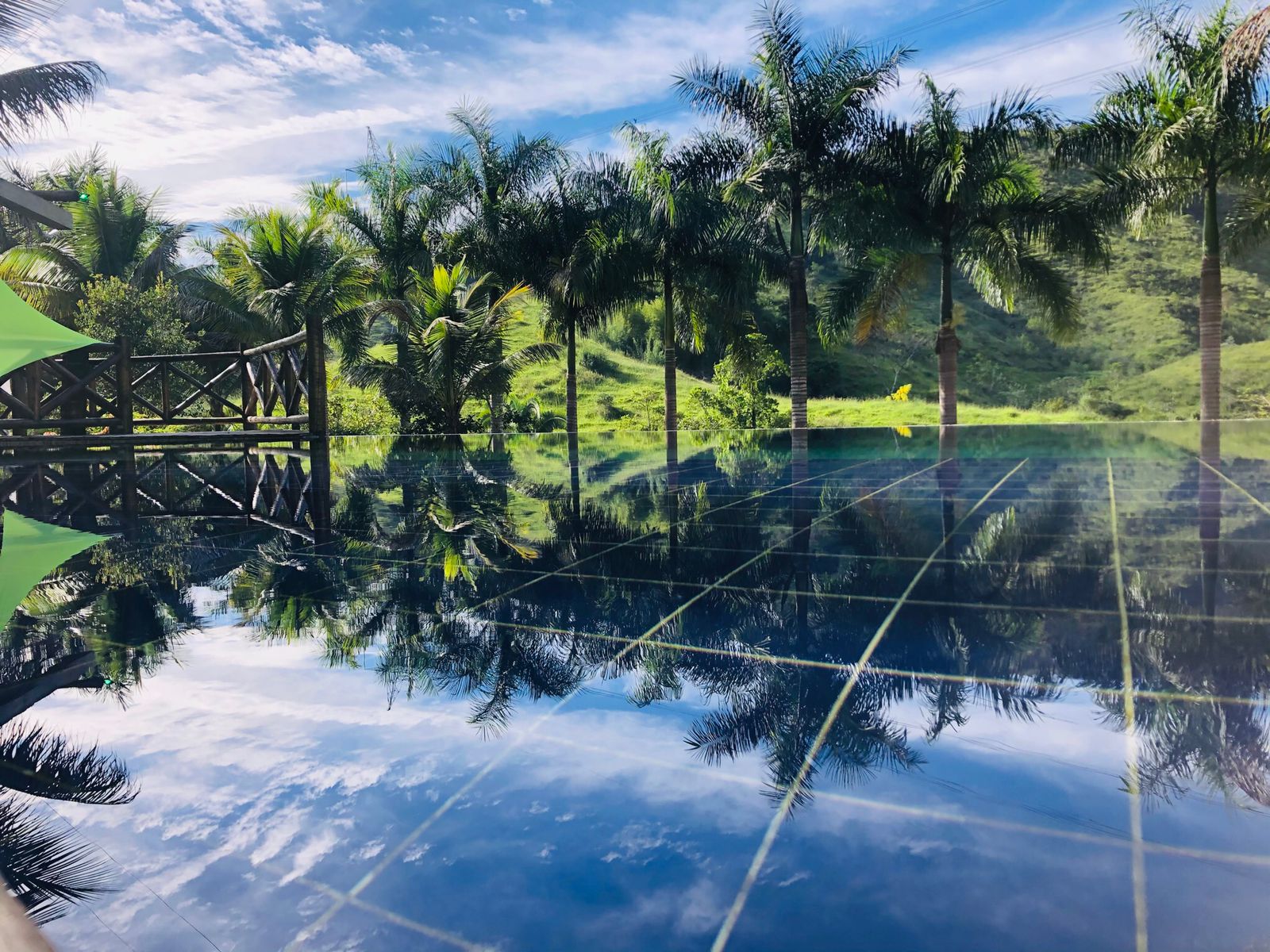 Piscina de borda infinita da Pousada Canto da Mata refletindo palmeiras e montanhas