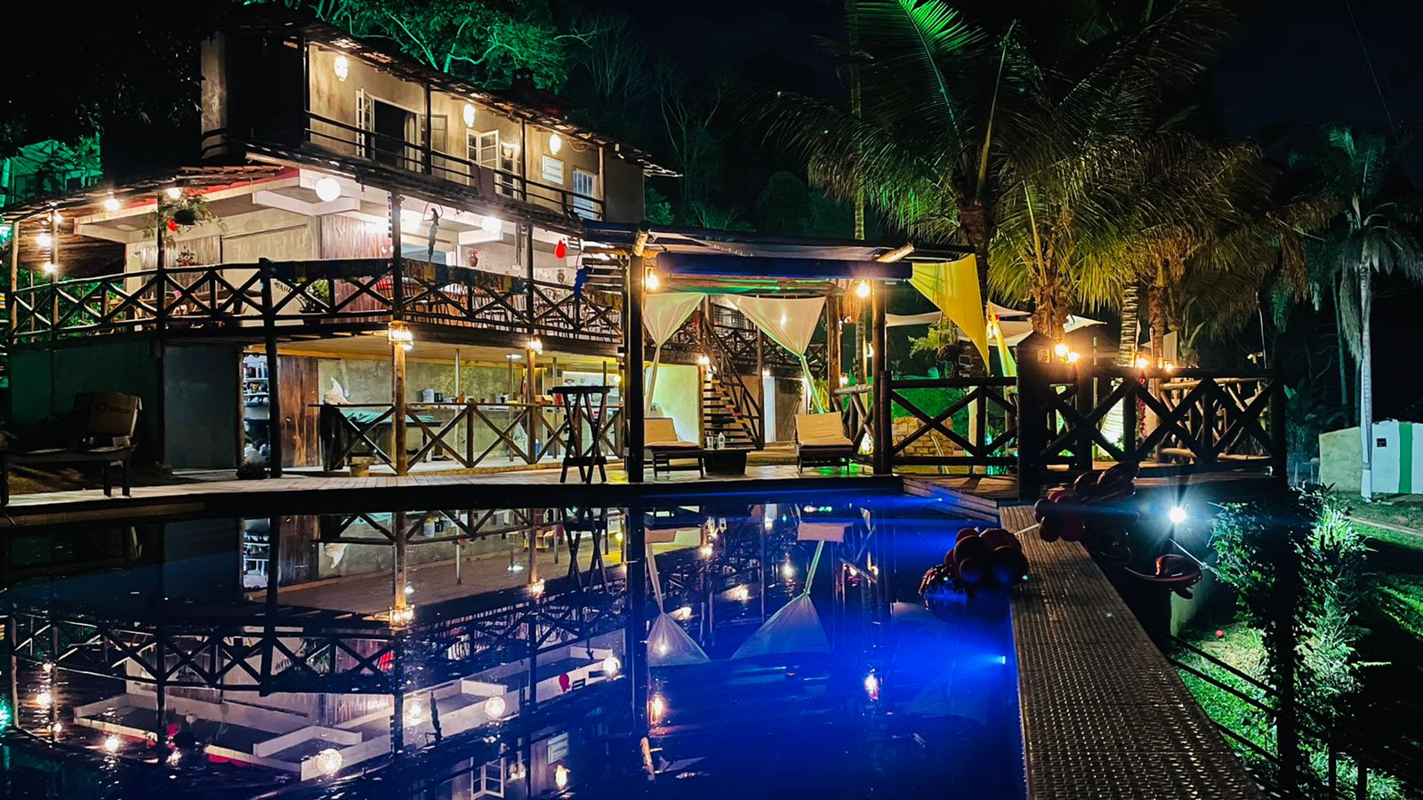 Sede da pousada iluminada refletida na piscina à noite